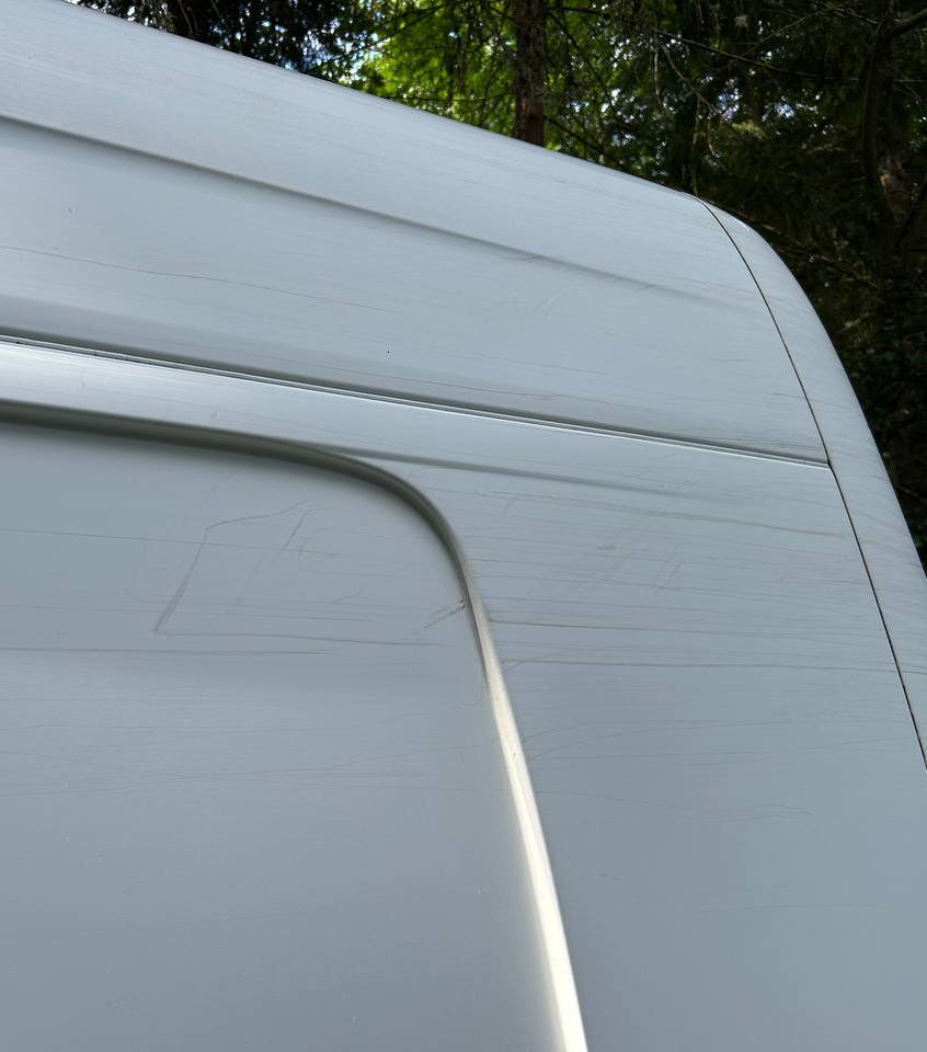 White van panel before paint correction, covered in visible scratches